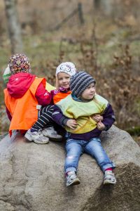 Barn som sitter utomhus på en sten. Foto.