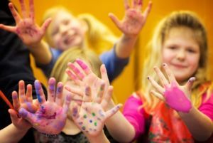 Barn som håller upp händer fulla med målarfärg.