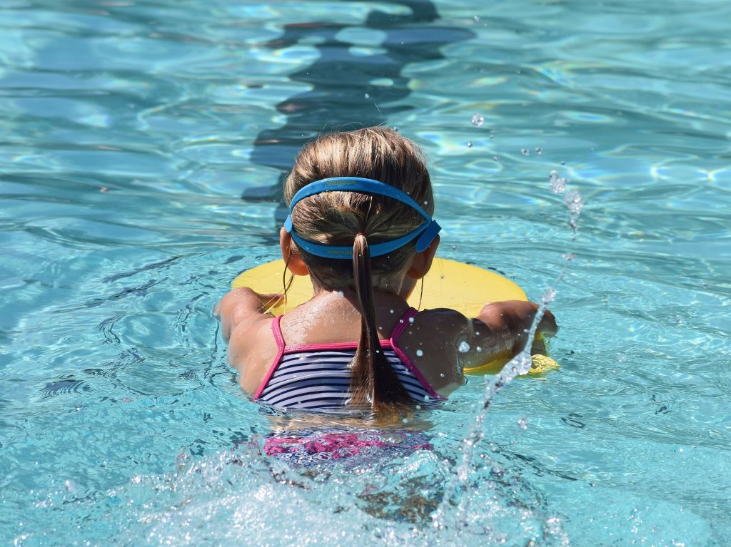 Bild på flicka som simmar med flytkudde.