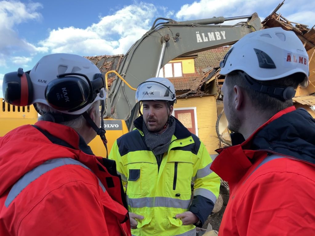 Bild på Patric Åberg i bygghjälm tillsammans två representanter från byggföretaget Älmsta.