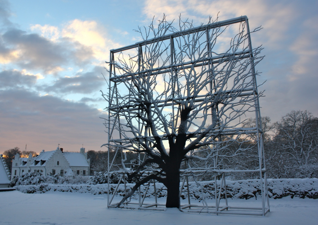 Vinterbild på Wanås. I förgrunden ett konstverk och i bakgrunden skymtar slottet.