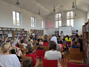 Elever lyssnar på författarbesök i ett bibliotek.