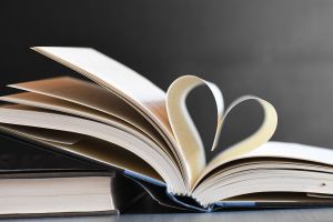 Bild på liggande böcker där blad från en bok formar ett hjärta.
