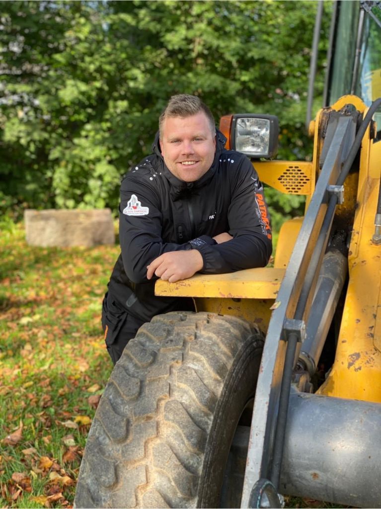 Bild på Patrik Isaksson vid en traktor.