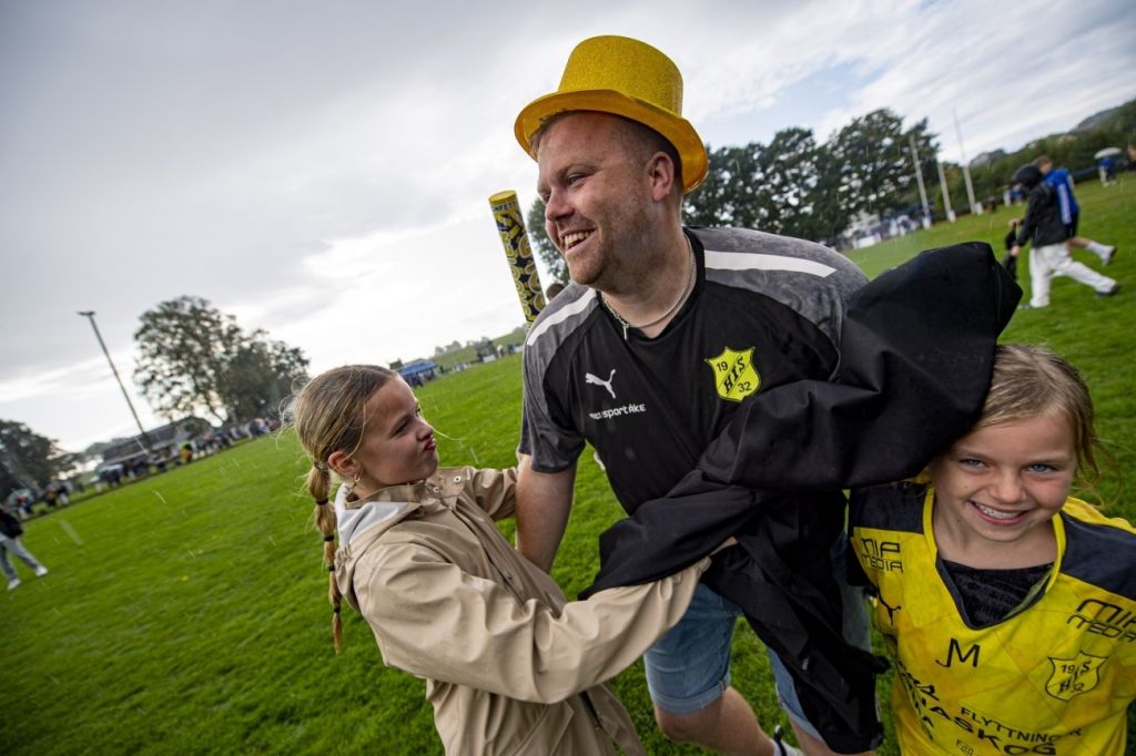 Bild på patrick isaksson i en guldhatt på en fotbollsplan tillsammans med två av sina döttrar.