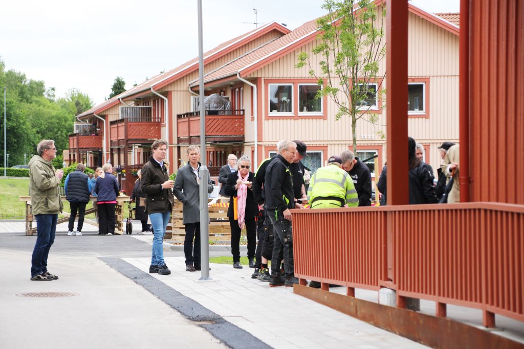 Bild på människor utomhus som samtalar och äter tårta tillsammans.