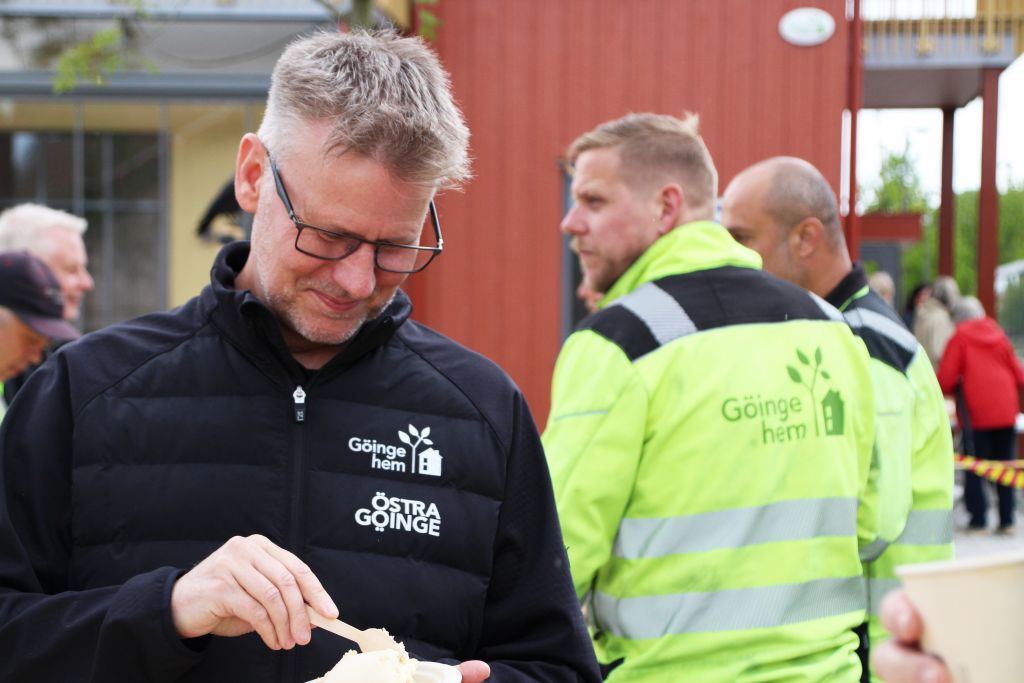Bild p en man som äter tårta med en tröja som det är både Göingehems och kommunens logga på. 